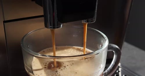 Modern coffee machine making americano into glass cup, view from above. Closeup