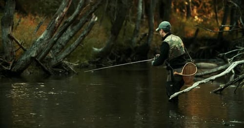 A Fisherman on a Small River Catches Trout with a Spinning Rod