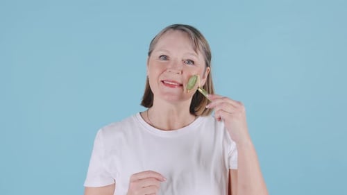 Woman Massages Face with Jade Facial Roller