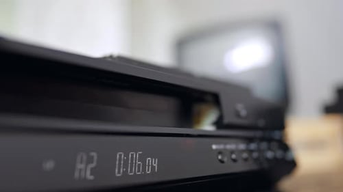 Aparece una cinta VHS de la grabadora. De cerca. La mano le quita la cinta al reproductor.