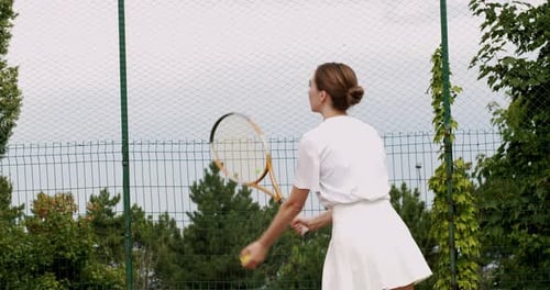Woman Serving Tennis Ball on Outdoor Court