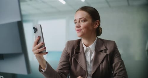 Businesswoman Video Chatting on Phone in Modern Office