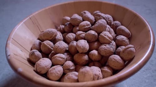 Walnuts Dropped into a Wooden Bowl Full