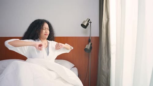 Woman Wakes Up and Stretches in Sunny Bedroom