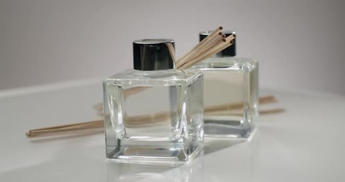Bouteilles de parfum en verre élégantes avec des bâtonnets de roseau sur fond blanc