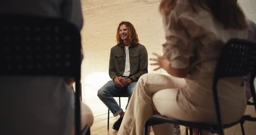 A Man with Curly Red Hair in a Green Gray Sweater Expresses His Problem at Groove Therapy in a White