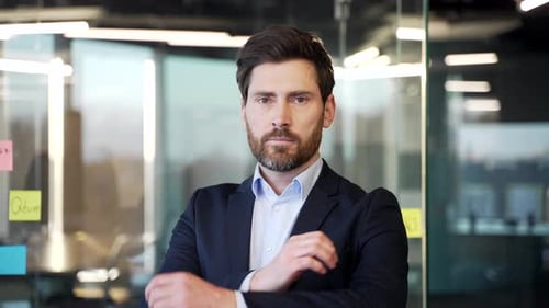 Confident businessman standing with arms crossed in modern office. Leadership, professionalism,