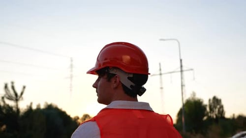 Engineer wearing hardhat in front of powerlines