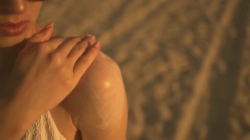 Woman is applying a sunscreen on a shoulder