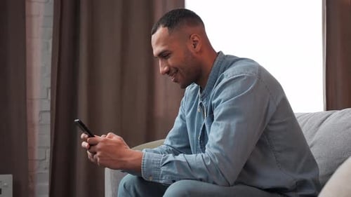 Man Using Smartphone While Relaxing on Couch