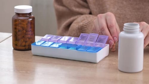 Person Filling Pill Organizer with Pills