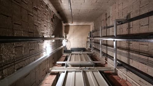 Elevator lift cabin moves up inside illuminated elevator shaft with hydraulics with many floors slow