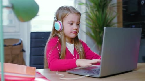 Girl Typing on Laptop Wearing Headphones Indoors