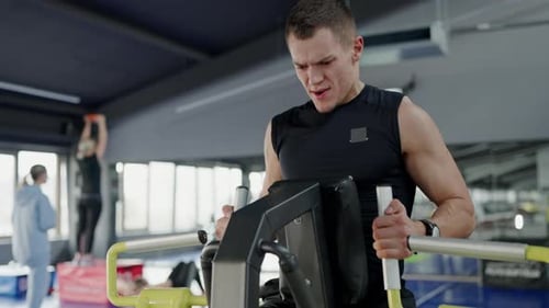 Strong Motivated Man Does Exercise for Back Muscles on Trainer in Sports Club