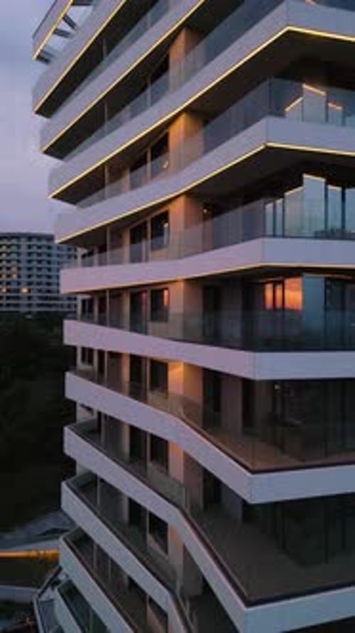 Modern Residential Building with Glass Balconies and LED Lighting at Sunset Urban Architecture and