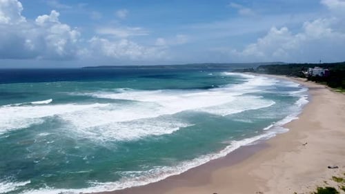 A vibrant beach with turquoise waves crashing, sunny day, aerial view