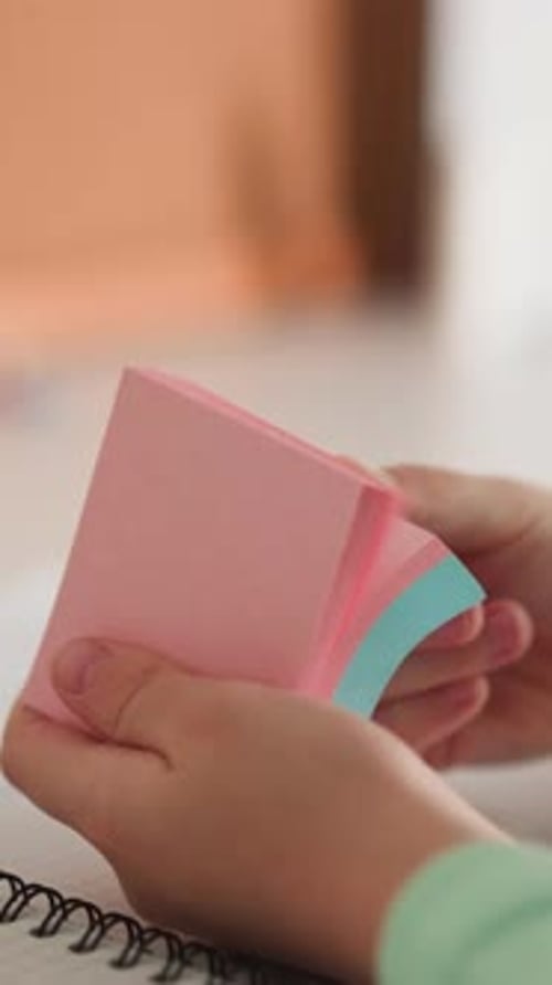 Little Girl Flips Sticky Papers in Pack Sitting at Desk