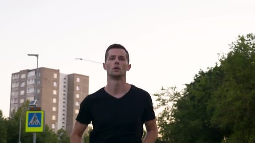 Close up shot of young running man. Athlete trains in the evening.