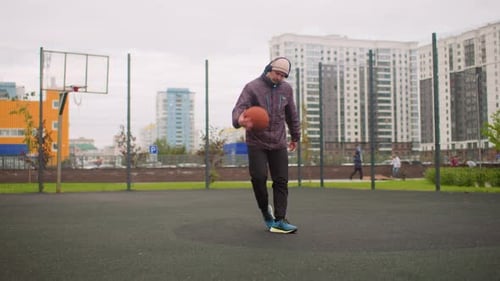 Single Athlete Honing Skills on Wet Urban Basketball Court Solitary Individual Works on Dribbling