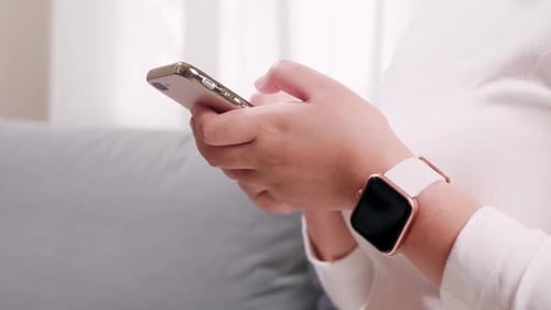 Woman's Hands Using Gold Cellphone and Smart Watch