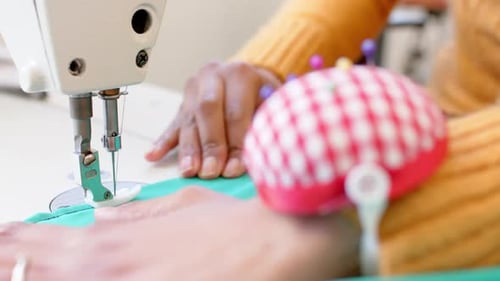 Biracial female fashion designer sewing fabric with sewing machine in studio, slow motion