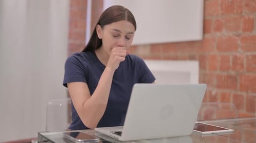 Young Woman Working on Laptop Coughing