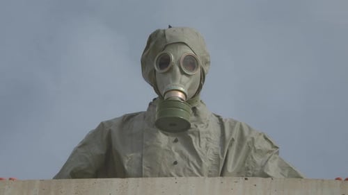 Hooded Figure in Gas Mask Standing Behind Wall