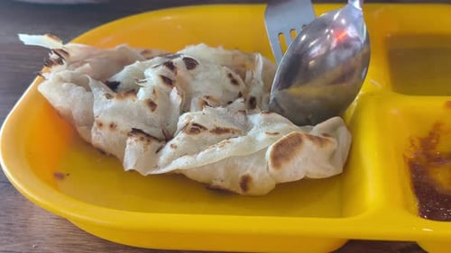Roti Canai clásico de Malasia servido con curry Dhal en un plato