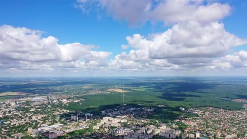 Panoramablick auf eine Stadt inmitten der grünen Natur. Stadtbild unter blauem Himmel mit weißen Wolken.