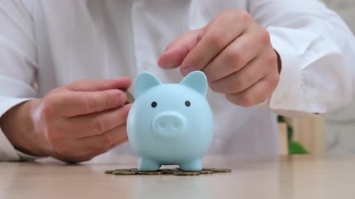 Man Putting Coins in Piggy Bank Money Saving Investment Pension Concept