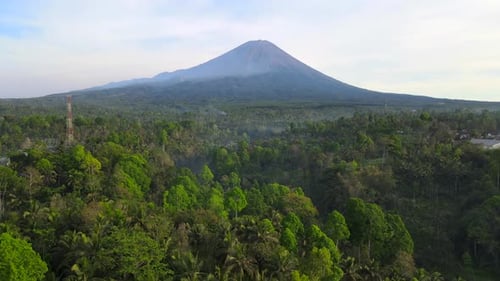 Drone move above thick jungle away from Semeru volcano at the background in Java Indonesia
