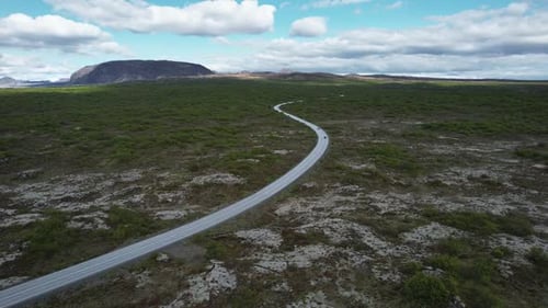 Route sans fin à travers le paysage nordique d'une vallée de montagnes volcaniques depuis la hauteur, trafic sur la route