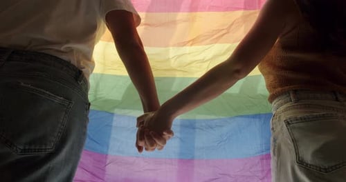 Close Up of Couple Holding Hands in Front of Flag