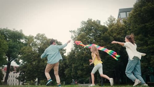 Happy Family Has Fun with Kite Running on Green Park Awn