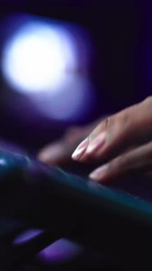 Manos humanas de cerca escribiendo en el teclado del portátil en la oscuridad: mujer negra irreconocible que trabaja en línea