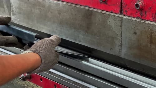 Close up shot of operator using bending to make indentations in iron plate sheets. Hand wearing clot