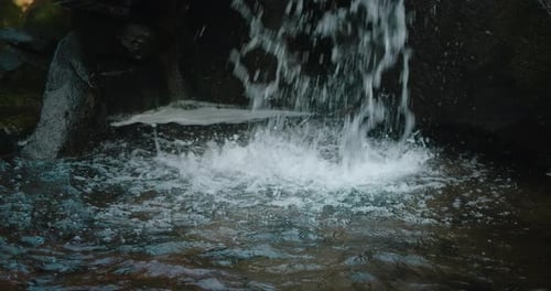 Close-up shot of clear fresh cold mountain water flowing in waterfall stream among rocks.