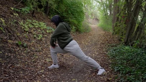 Woman Stretching Outdoors on Leafy Forest Path