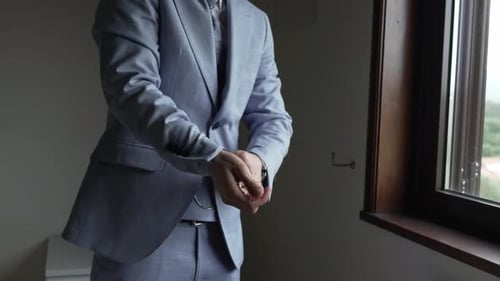 Man Adjusts Cufflink in Light Blue Suit