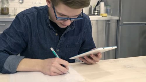 Teen with Tablet Studying and Taking Notes at Home