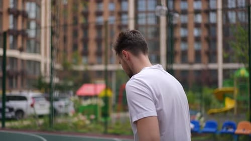 Young Adult Practicing Basketball on Urban Court