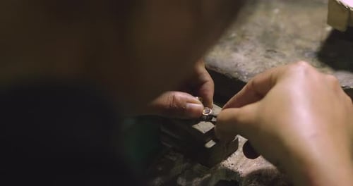 Close-up of a hand of a goldsmith who builds a precious jewel with valuable diamonds. To make the