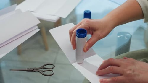 Person Gluing White Paper at Glass Table