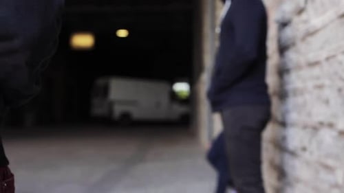 Hand exchanges small packet in urban alleyway