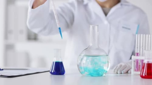 Scientist Adding Solution to Flasks in Lab