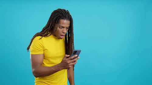 Surprised Latin Man with Dreadlocks Using a Mobile Phone