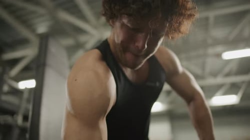 Muscular Man Performing Seated One-Arm Dumbbell Curls on Gym Bench