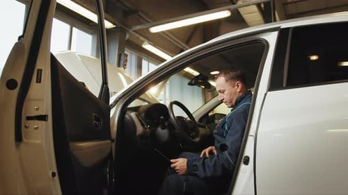 Servicemann, der mit Laptop in einer Werkstatt Autodiagnosen durchführt