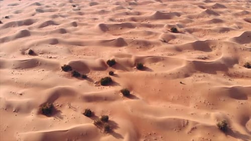 A vast red sand desert reveal. Drone aerial cinematic shot. 4K.