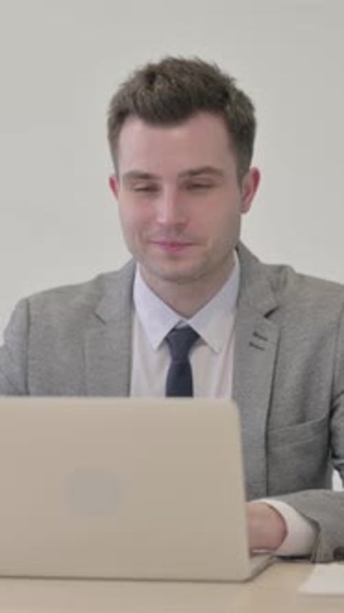 Smiling Man in Suit Waves During Video Call